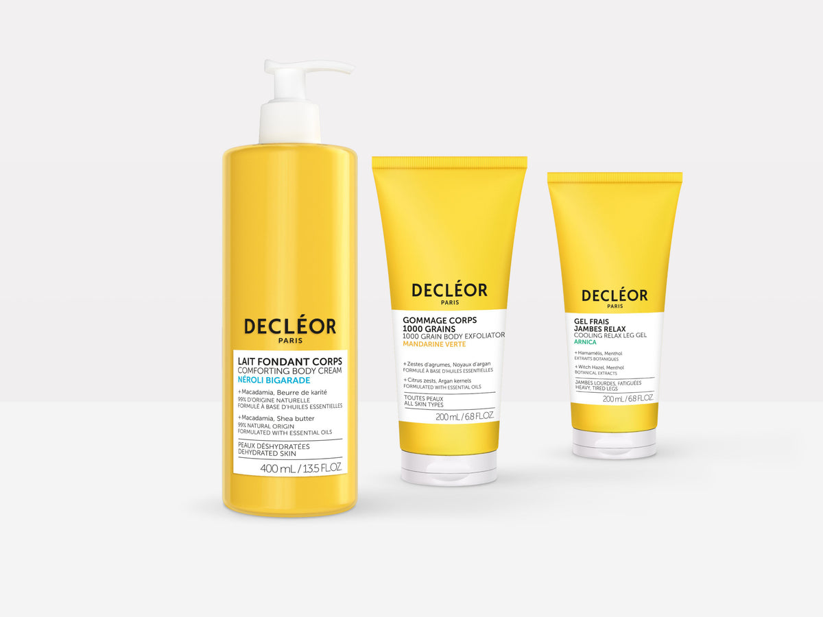 Decleor body care trio in bright yellow packaging, including Neroli Bigarade Comforting Body Cream, 1000 Grain Body Exfoliator and Relaxing Legs Gel, on a white background