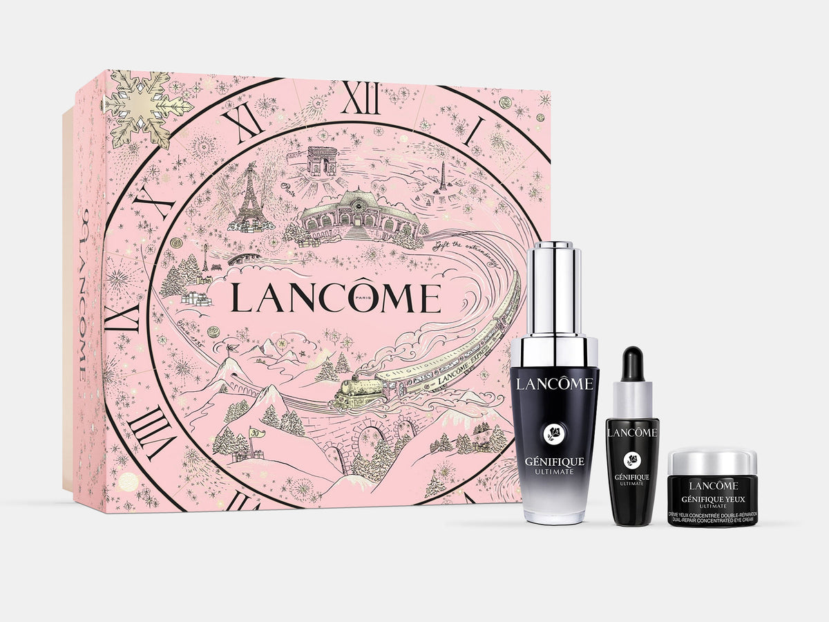Lancome Genifique Ultimate serum gift set with a pink box illustrated with Paris landmarks and a clock face, alongside the serum, a mini serum and an eye cream, on a white background