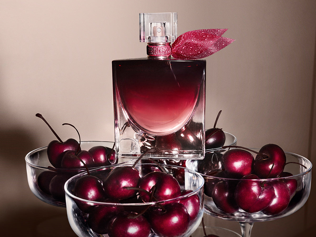 Lancome La Vie Est Belle L'Elixir Very Cherry perfume with a glittering pink bow, surrounded by glass bowls of dark cherries